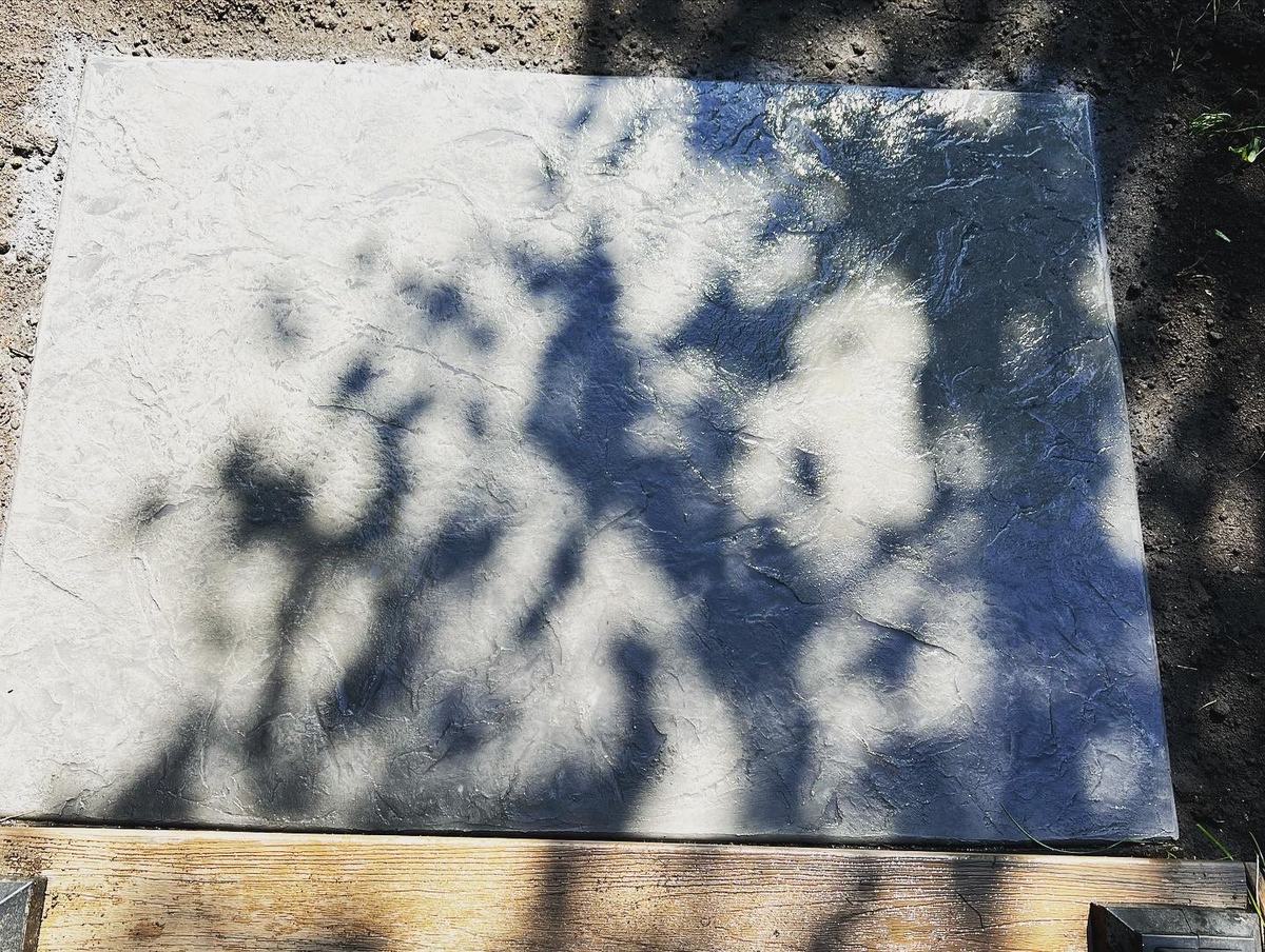 Colored concrete slab curing in its wood forms with a textured surface