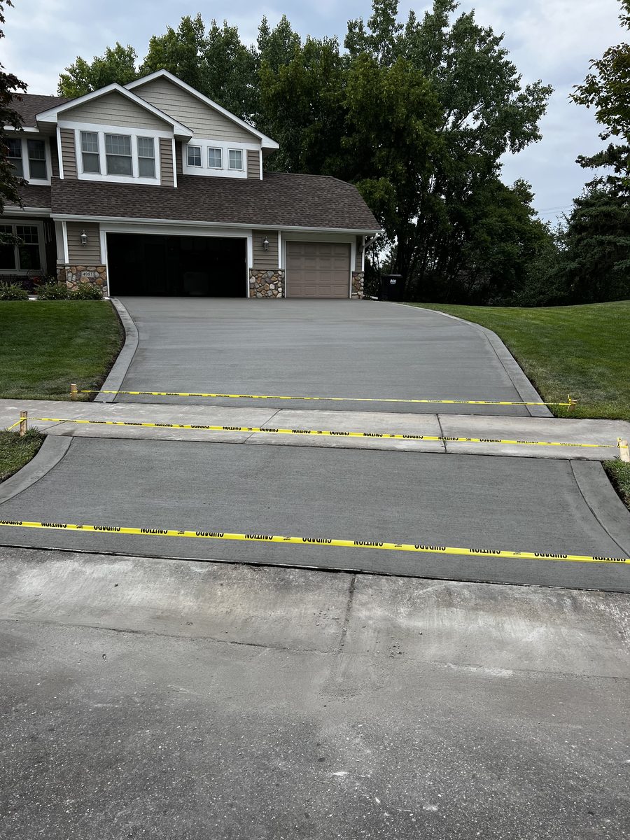 Freshly finished concrete driveway at a two-story home, taped off to cure