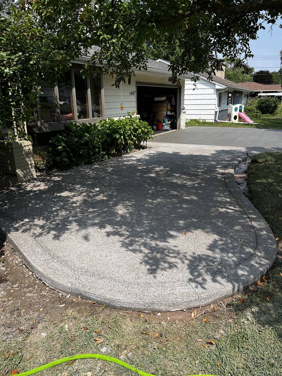 Exposed aggregate concrete driveway with a curved broom-finish border in Columbia Heights, MN