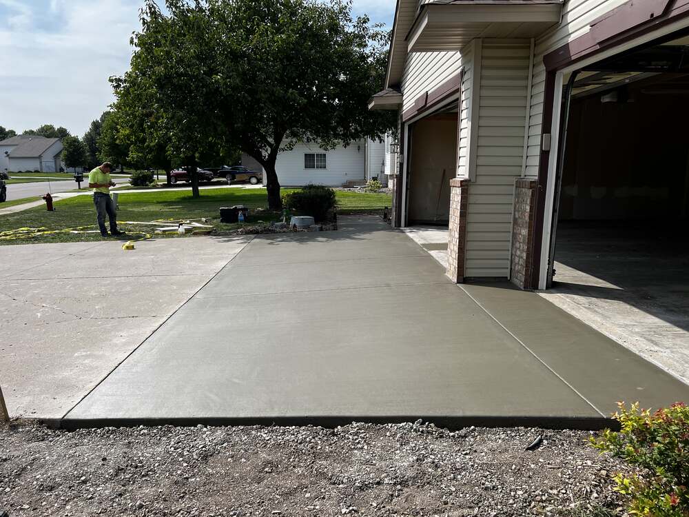 Freshly poured concrete garage apron and driveway approach at a two-door garage with brick columns