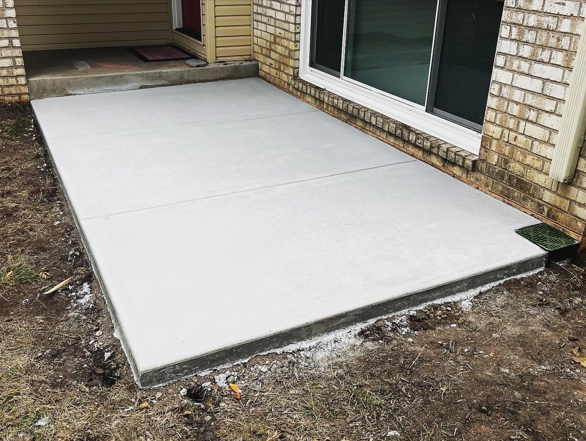 Concrete patio slab poured against a brick home at a sliding-door walkout