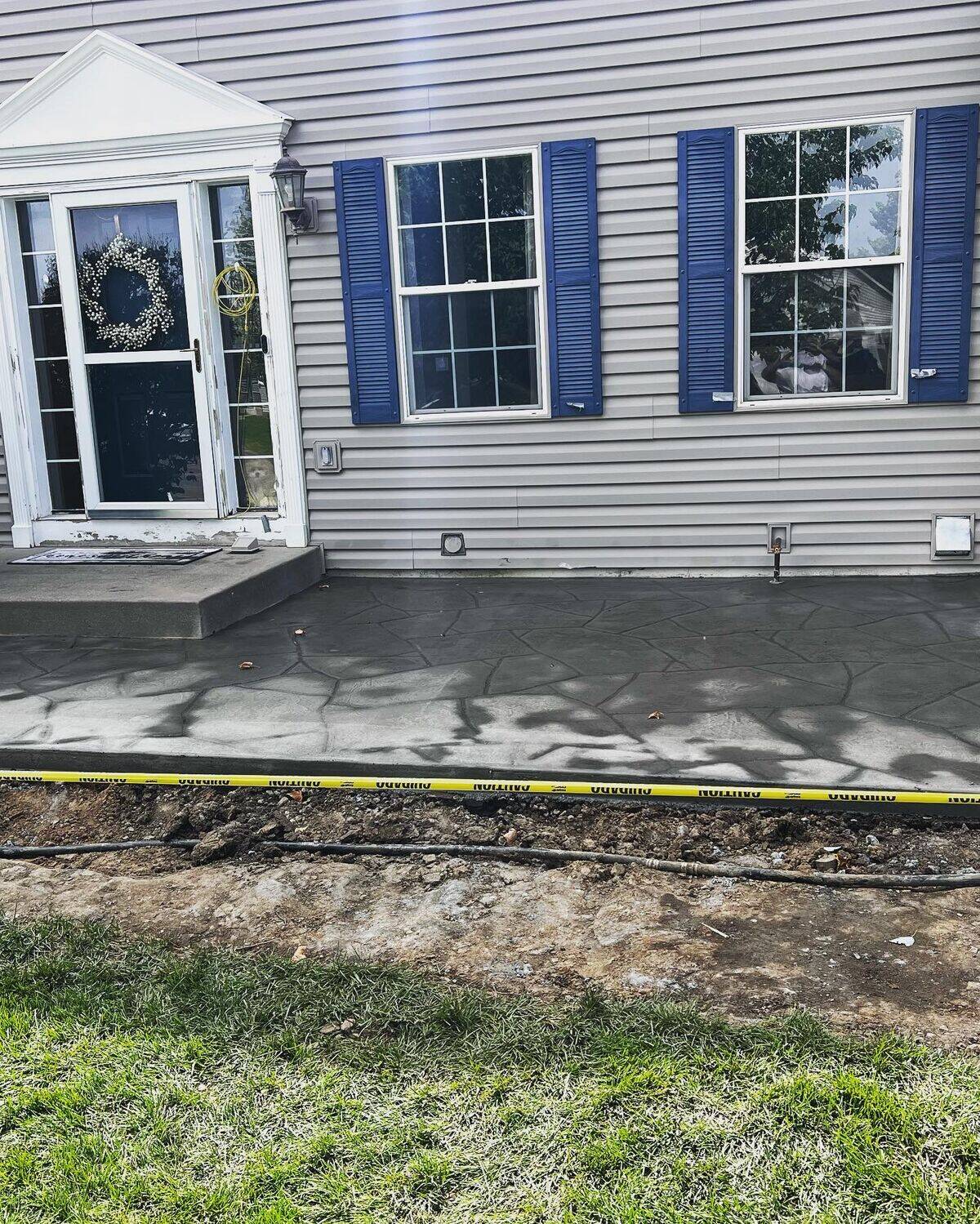 Freshly stamped flagstone-pattern concrete walkway at a front entry, charcoal finish